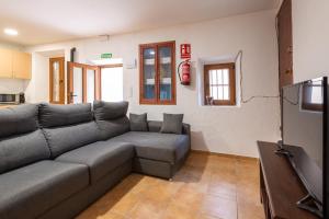 Una sala de estar con un sofá y un televisor. en Casa cueva El establo del Júcar, en Alcalá del Júcar