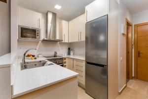 a kitchen with a stainless steel refrigerator and white cabinets at Gracia Gem Ac, Near Fontana Metro, Hipster Haven in Barcelona