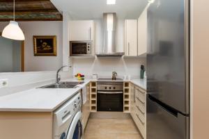 cocina con armarios blancos y nevera de acero inoxidable en Gracia Gem Ac, Near Fontana Metro, Hipster Haven, en Barcelona