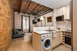 a kitchen with a washer and dryer next to a brick wall at Gracia Gem Ac, Near Fontana Metro, Hipster Haven in Barcelona