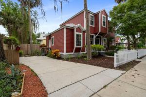 a red house with a white fence and a sidewalk at Whitefish Lodge in St. Augustine