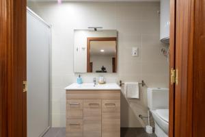 Un baño con lavabo, inodoro y espejo. en Casa cueva El establo del Júcar, en Alcalá del Júcar