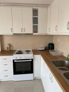 a kitchen with white cabinets and a stove and a sink at Kate House in Agioi Apostoli