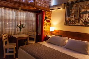 a bedroom with a bed and a table and a window at Pousada Mar de Dentro in Florianópolis