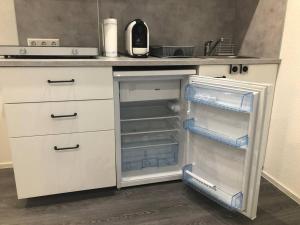 eine weiße Küche mit leerem Kühlschrank und offener Tür in der Unterkunft Modernes 1-Zimmer-Apartment im Herzen Oberkochens in Oberkochen