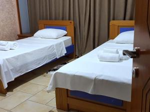 two beds in a room with white sheets and towels at Jessie's apartments in Durrës