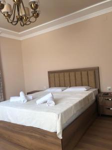 Un dormitorio con una cama con sábanas blancas y una lámpara de araña. en Guest House Bagrationi en Batumi