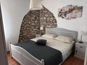 1 dormitorio con 1 cama con pared de piedra en Villa Giovanna en Rakalj