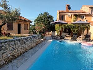 a swimming pool with chairs and umbrellas next to a house at Villa Giovanna in Rakalj