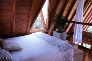 1 dormitorio con 1 cama blanca en una cabaña de madera en Glamping con jacuzzi cerca a Medellin en Guarne