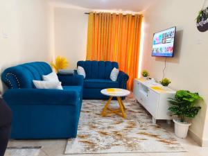 a living room with two blue chairs and a tv at DANA HOMES in Nairobi