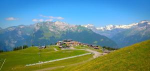 un bâtiment sur une colline avec des montagnes en arrière-plan dans l'établissement Appartement au pied des pistes, à Samoëns