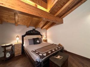 a bedroom with a large bed with a wooden ceiling at Nido Mountain Apartment in Castione della Presolana