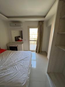 a bedroom with a bed and a kitchen with a window at Alamein apartments prime residence in El Alamein