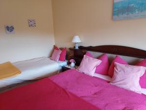 two beds in a room with pink sheets and pillows at Tullaleagan Guesthouse in Oughterard