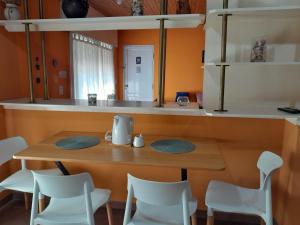 a table and chairs in a kitchen with orange walls at Alojamiento Passiflora I in Villa Elisa