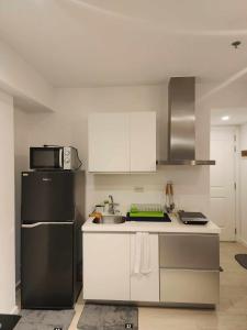 Il comprend une cuisine équipée d'un réfrigérateur noir et de placards blancs. dans l'établissement Azure Urban Resort Residences, à Manille