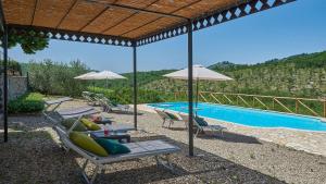uma piscina com espreguiçadeiras e guarda-sóis ao lado de uma piscina em Mulinaccio di Badia em Gaiole in Chianti