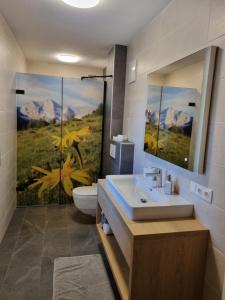 a bathroom with a sink and a toilet with a painting at Greidlhof Alpstyle Apartments in Fügen