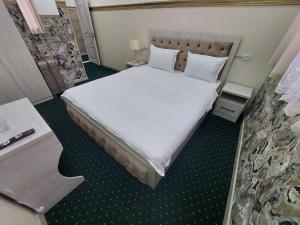 um quarto com uma cama grande com lençóis brancos e almofadas em SEMURG HOTEL em Tashkent
