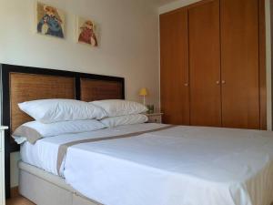 1 dormitorio con 1 cama grande con sábanas y almohadas blancas en Apartamento junto al mar con WiFi y piscina, en Sagunto