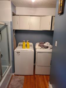 uma lavandaria com dois sapatos amarelos numa máquina de lavar e secar roupa em Le1226 Apartment em Edmundston