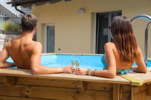 Ein Mann und eine Frau sitzen in einem Whirlpool mit Gläsern Champagner in der Unterkunft Villa Carmen in Arco