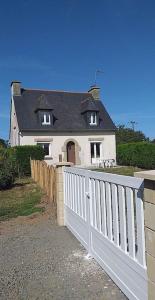 Uma casa branca com uma cerca branca à frente. em Maison bretonne em Plourhan