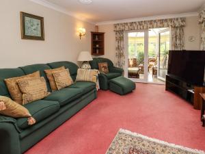 a living room with a green couch and a television at Tregarthens in Church Stretton