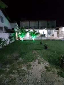 un patio con 2 palmeras y luces verdes en Casa Temporada Privativa RJ en Iguaba Grande