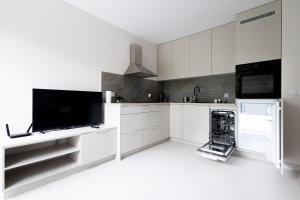 羅茲的住宿－Brzeska 22，厨房配有白色橱柜和平面电视。