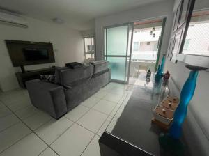 Una sala de estar con un sofá y un televisor. en Apto 200m mar de Cabo Branco, en João Pessoa