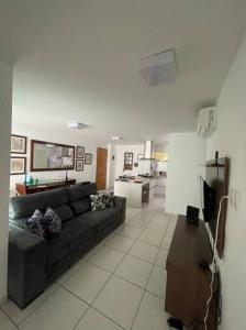 Una sala de estar con un sofá y una cocina. en Apto 200m mar de Cabo Branco, en João Pessoa