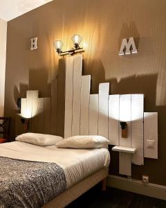 a bedroom with a bed with two lights on the wall at Hotel Le Midi Clermont-Cournon in Cournon-dʼAuvergne