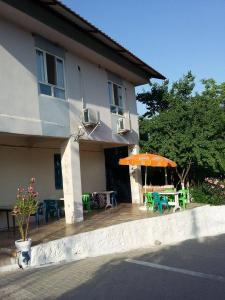 ein Haus mit einem orangenen Regenschirm, Tischen und Stühlen in der Unterkunft Nemrut Dağı Işik Pansi̇on in Karadut