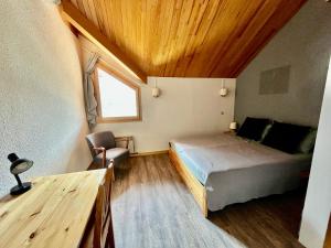 um quarto com uma cama e um tecto de madeira em VAUJANYLOCATIONS - LA FARE 30 em Vaujany