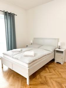 een wit bed in een slaapkamer met een houten vloer bij Jen tak spolu - apartmán Znojmo in Znojmo