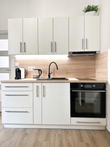 una cocina con armarios blancos y horno negro en Jen tak spolu - apartmán Znojmo en Znojmo