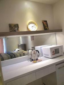 a counter with a microwave and a clock on a wall at Cozy Studio with Beautiful View & FREE Netflix Access in Manila