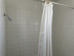 y baño con ducha con cortina blanca. en Ski's Western Motel en Great Falls