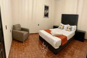 een slaapkamer met een bed en een stoel bij Viñedos y Peña - La Gladiola in Ezequiel Montes