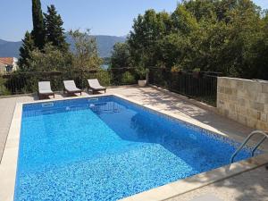 una piscina azul con 2 sillas junto a ella en Annabell apartman, en Tivat