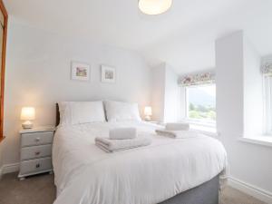a bedroom with a white bed with two towels on it at Squirrel Cottage in Keswick