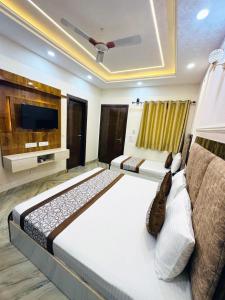 a bedroom with two beds and a flat screen tv at Frankstay By Hotel SAMRAT RESIDENCY 10 Mints Walking Distance Nizamuddin Railway Station in New Delhi