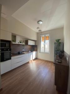 a large kitchen with white cabinets and a wooden floor at La Maison de Jeanne in Narbonne