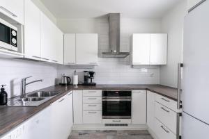 Una cocina blanca con gabinetes blancos y un fregadero. en Vitosjussi, en Hämeenlinna