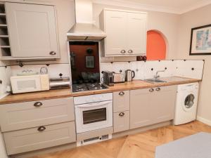 a kitchen with white cabinets and a stove top oven at Simonside Apartment in Morpeth