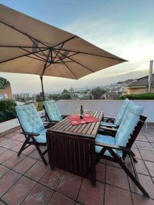 a table and chairs with an umbrella on a patio at Casa familiar en la playa con piscina in Teià