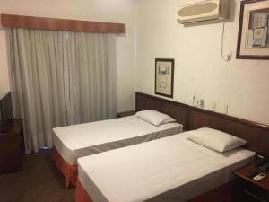 a hotel room with two beds and a tv at Summit Flat Service in São José dos Campos