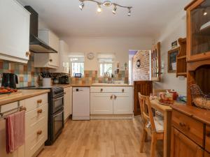a kitchen with white cabinets and a wooden floor at Green Gate Cottage in Southwold